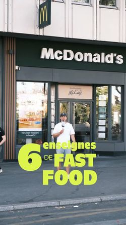 Façade du restaurant McDonald's avec un employé debout devant l'entrée principale sur un trottoir urbain.