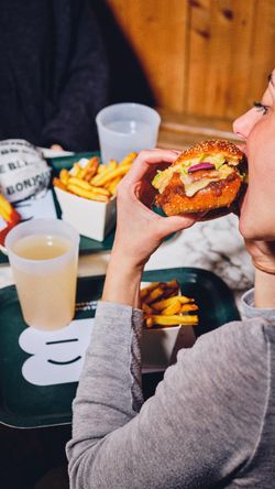 Personne tenant un burger bio avec frites et boisson sur plateau au restaurant Bioburger Bordeaux Gambetta.