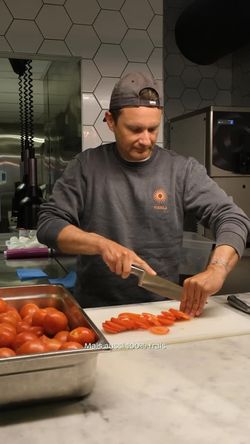 Chef du restaurant bio Bioburger Le Marais en train de couper des tomates fraîches dans une cuisine hexagonale.