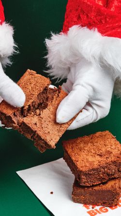 Délicieux brownies en portions, posés sur un emballage, avec des mains gantées de blanc.