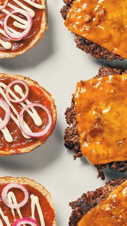 Quatre burgers ouverts avec galettes de viande et fromage fondu, garnis de sauce et tranches d'oignon rouge.