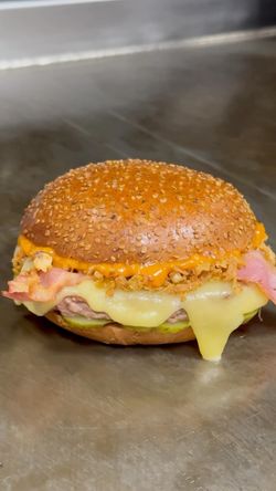 Burger bio avec fromage fondu, bacon croustillant et sauce dans un pain aux graines de sésame chez Bioburger.