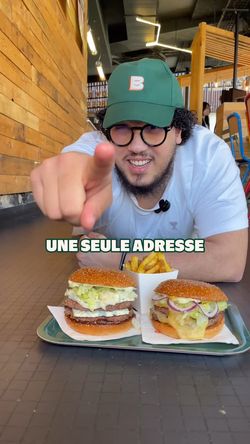 Deux burgers sur une table, un avec fromage et un autre vegan, dans un cadre décontracté.