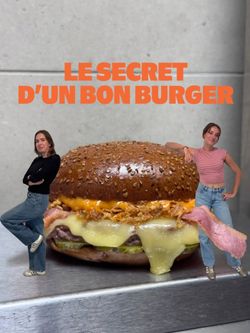 Burger bio avec fromage fondu, oignons frits et jambon sur pain aux graines, présenté par deux femmes à côté.