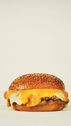 Burger bio avec fromage fondu et pain aux graines de sésame, présenté sur un fond clair, typique du restaurant burger bio.
