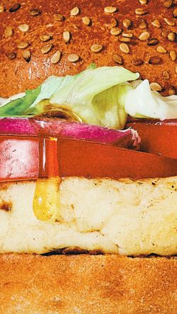 Un burger bio avec de la laitue, des oignons rouges et une sauce qui coule sur le pain. Restaurant Bioburger.