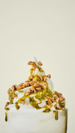 Dessert glacé au coulis vert et éclats croustillants, présenté dans un récipient blanc minimaliste.