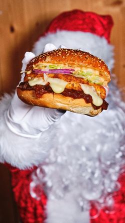 Hamburger dans un pain à sésame avec garniture, servi par une main gantée de blanc.