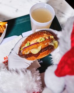 Dégustation d'un burger bio savoureux, accompagné de frites et d'une boisson, sur un plateau.