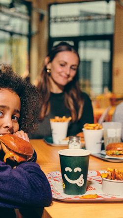 Enfant mangeant un burger accompagné de frites dans un restaurant bio convivial et adapté aux familles à Strasbourg.