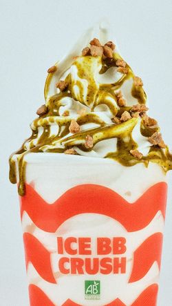 Glace douce avec sauce verte et éclats croquants dans un gobelet blanc orné de rouge Bioburger.