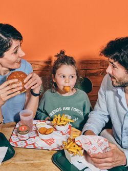 Repas familial au restaurant burger bio avec frites, nuggets, et boissons sur plateau à Bioburger Gobelins.