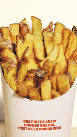 Frites épaisses servies dans un emballage blanc avec texte rouge du restaurant burger bio Bioburger Wacken.