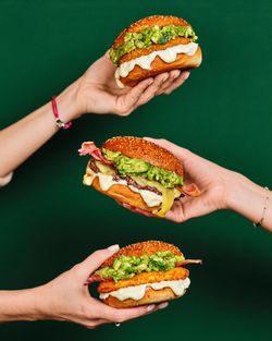 Trois burgers avec garnitures variées, présentés sur un fond vert, illustrant l'offre du restaurant Bioburger Metz.