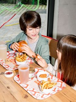 Un moment convivial au Bioburger Oxygen avec des enfants savourant des burgers bio et des frites.