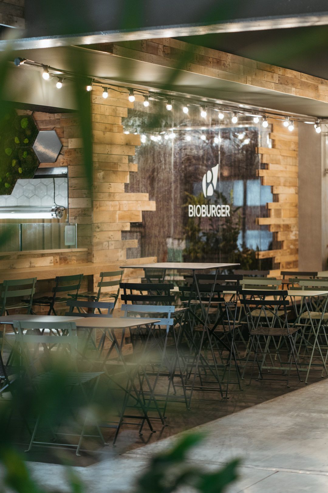Espace dinatoire du restaurant Bioburger avec des tables et des chaises en métal, mur en bois et ambiance moderne.