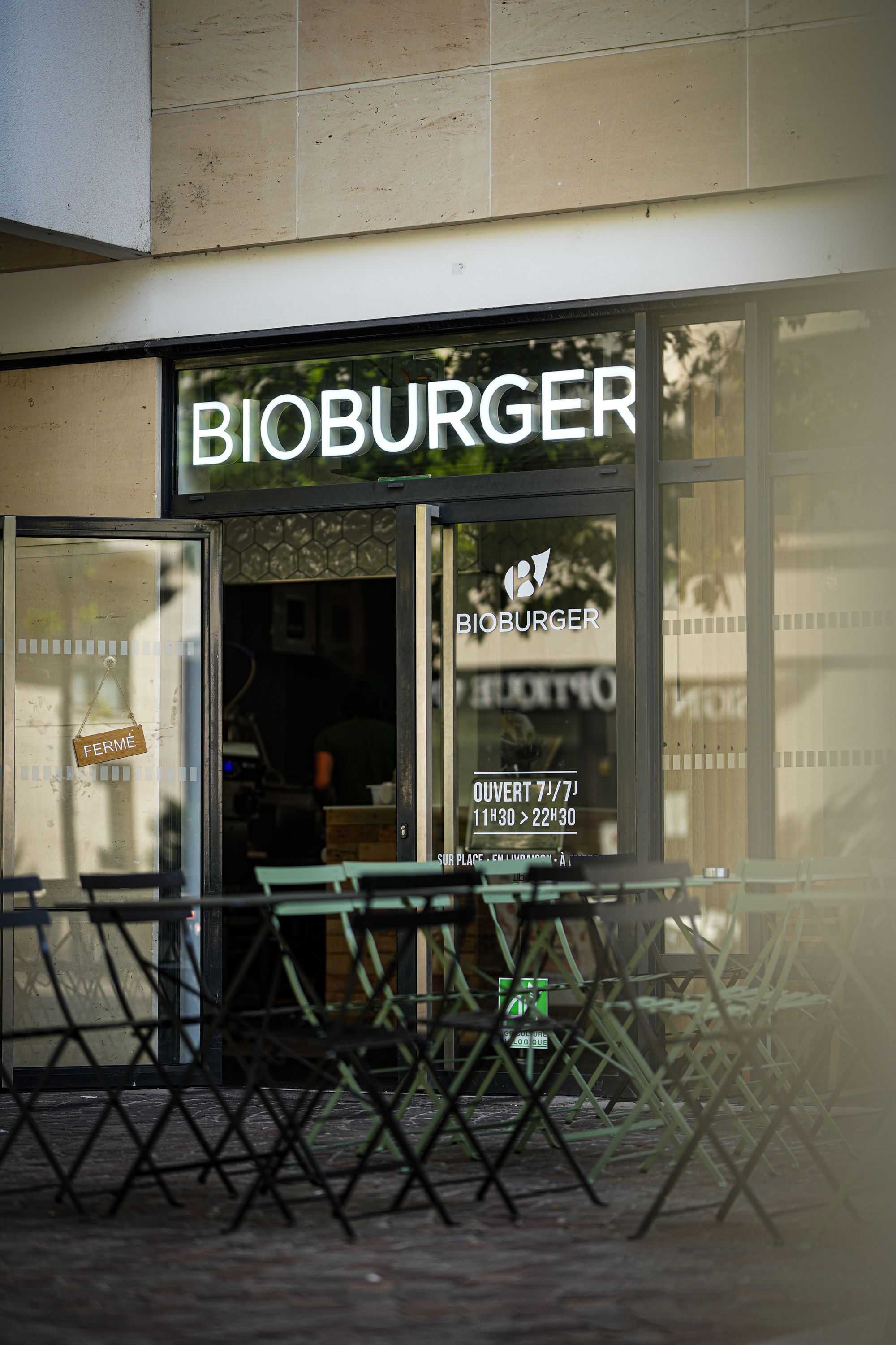 Façade du restaurant Bioburger Batignolles avec des tables de jardin. Spécialisé dans les burgers bio et végétariens.
