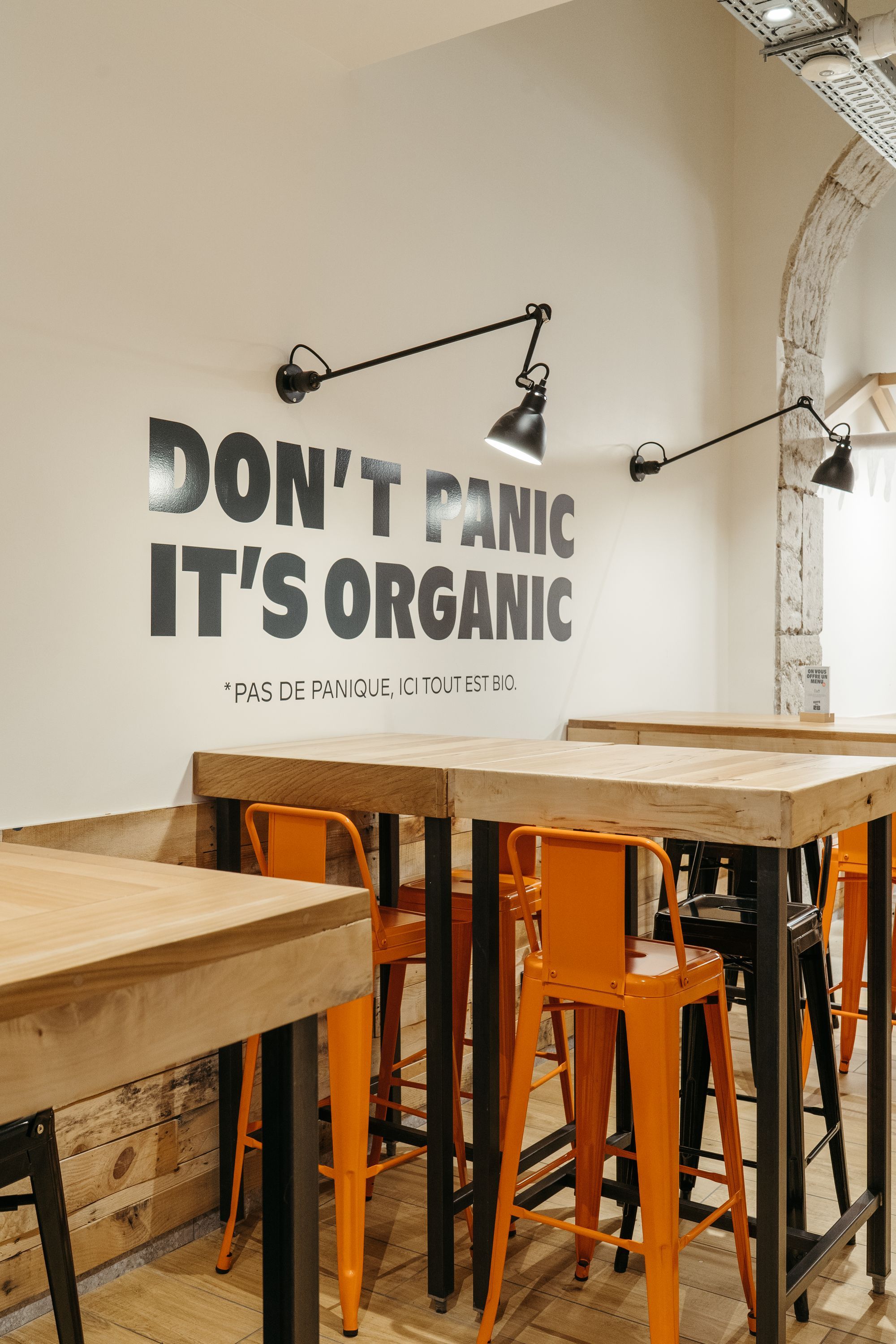 Ambiance d'un restaurant avec des tables en bois et des chaises orange, décoration orientée bio.