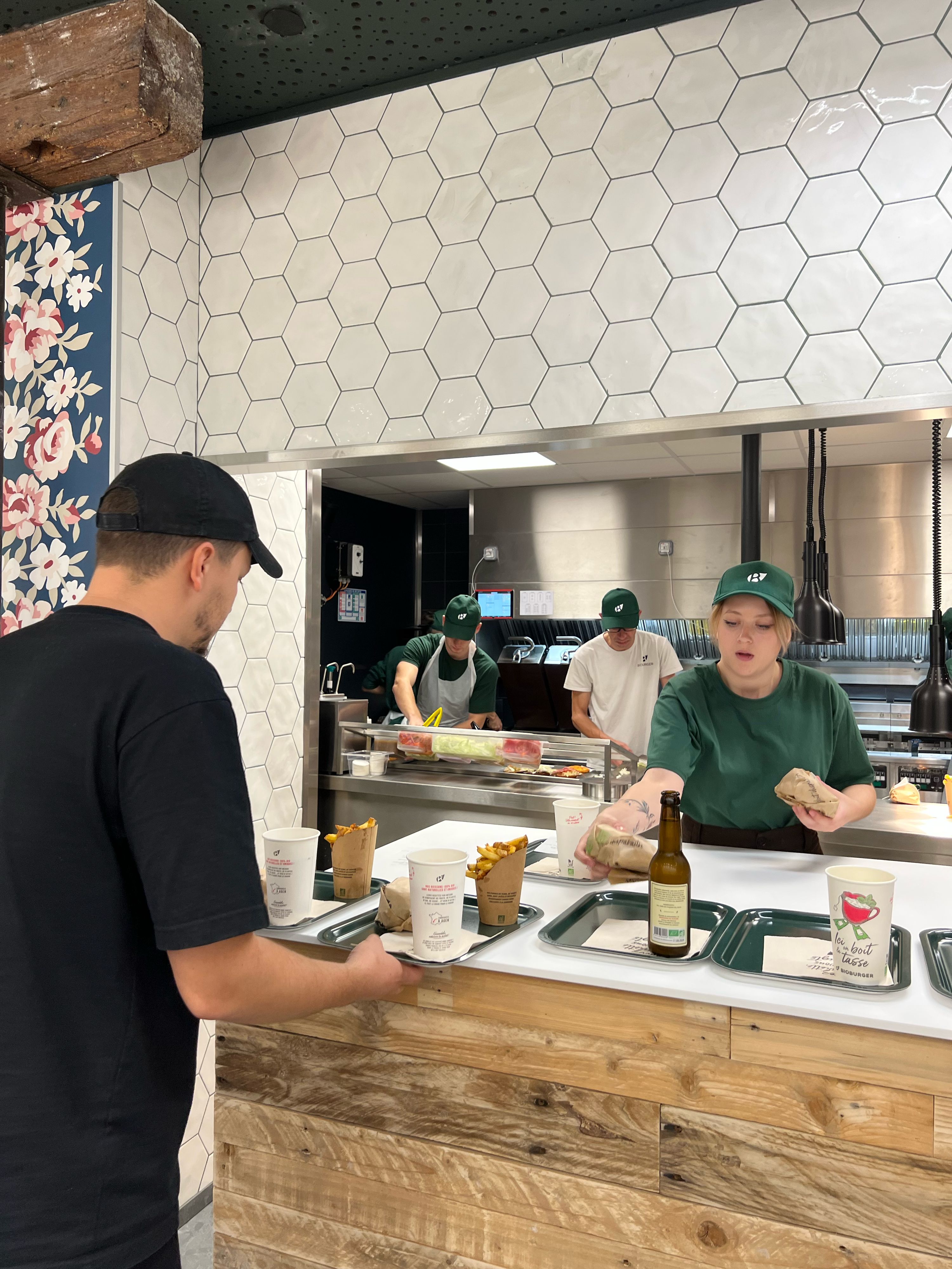 Commande de burger bio, fries et boisson dans le restaurant Bioburger, avec équipe en action.