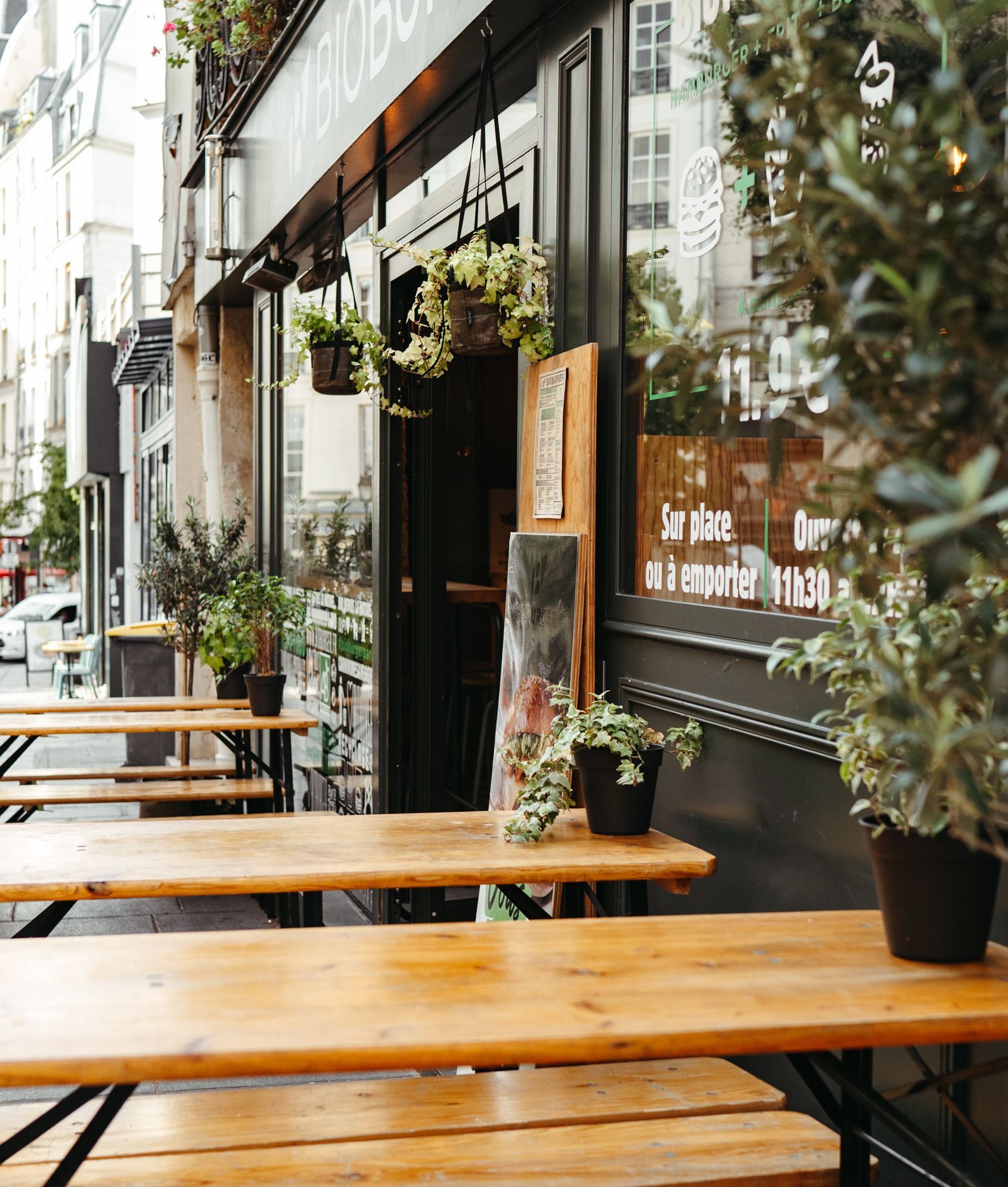 Terrasse du Bioburger Montorgueil avec tables en bois et plantes en pot.