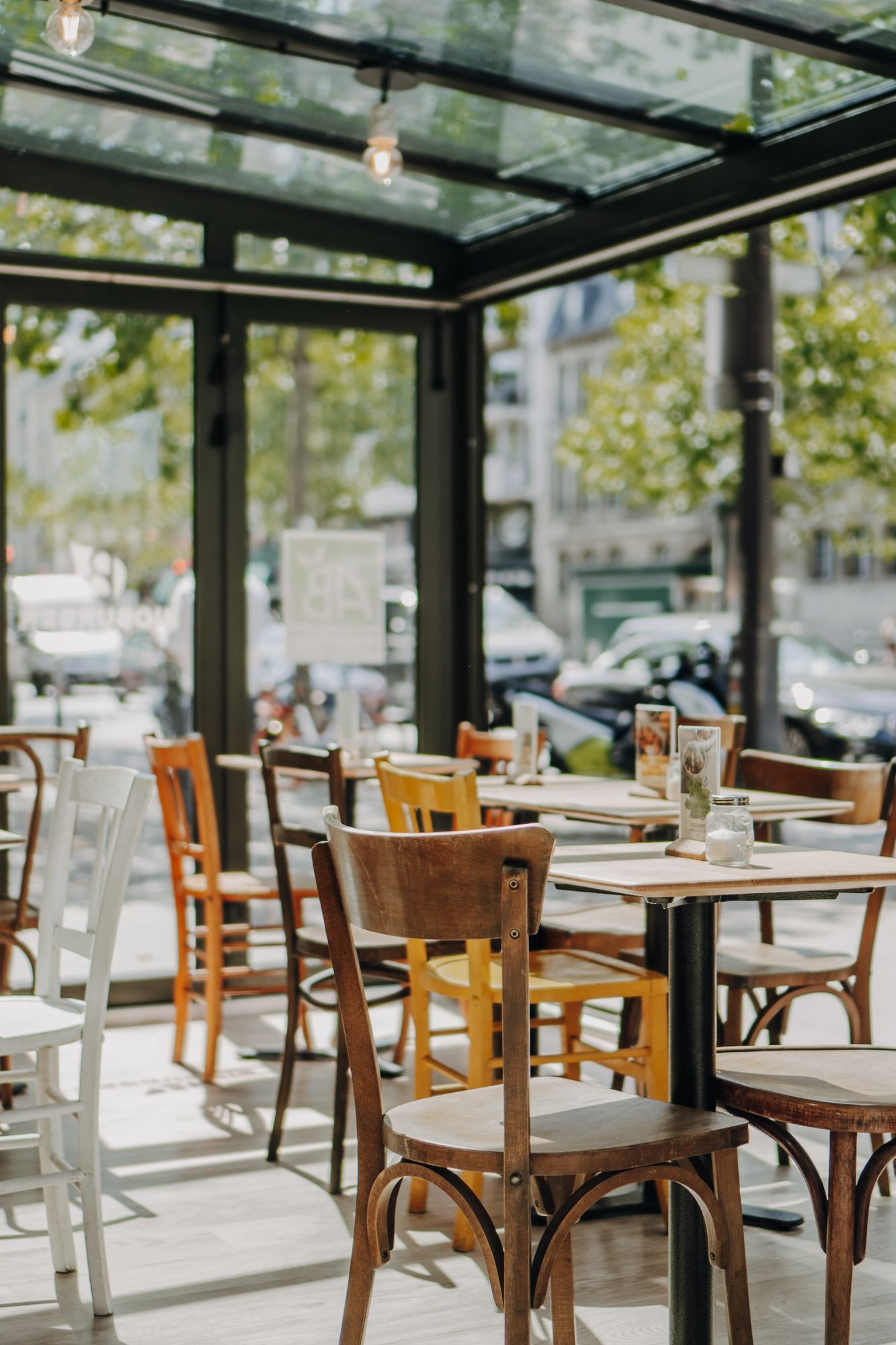 Terrasse lumineuse avec des tables et chaises en bois, créant une ambiance confortable et accueillante.