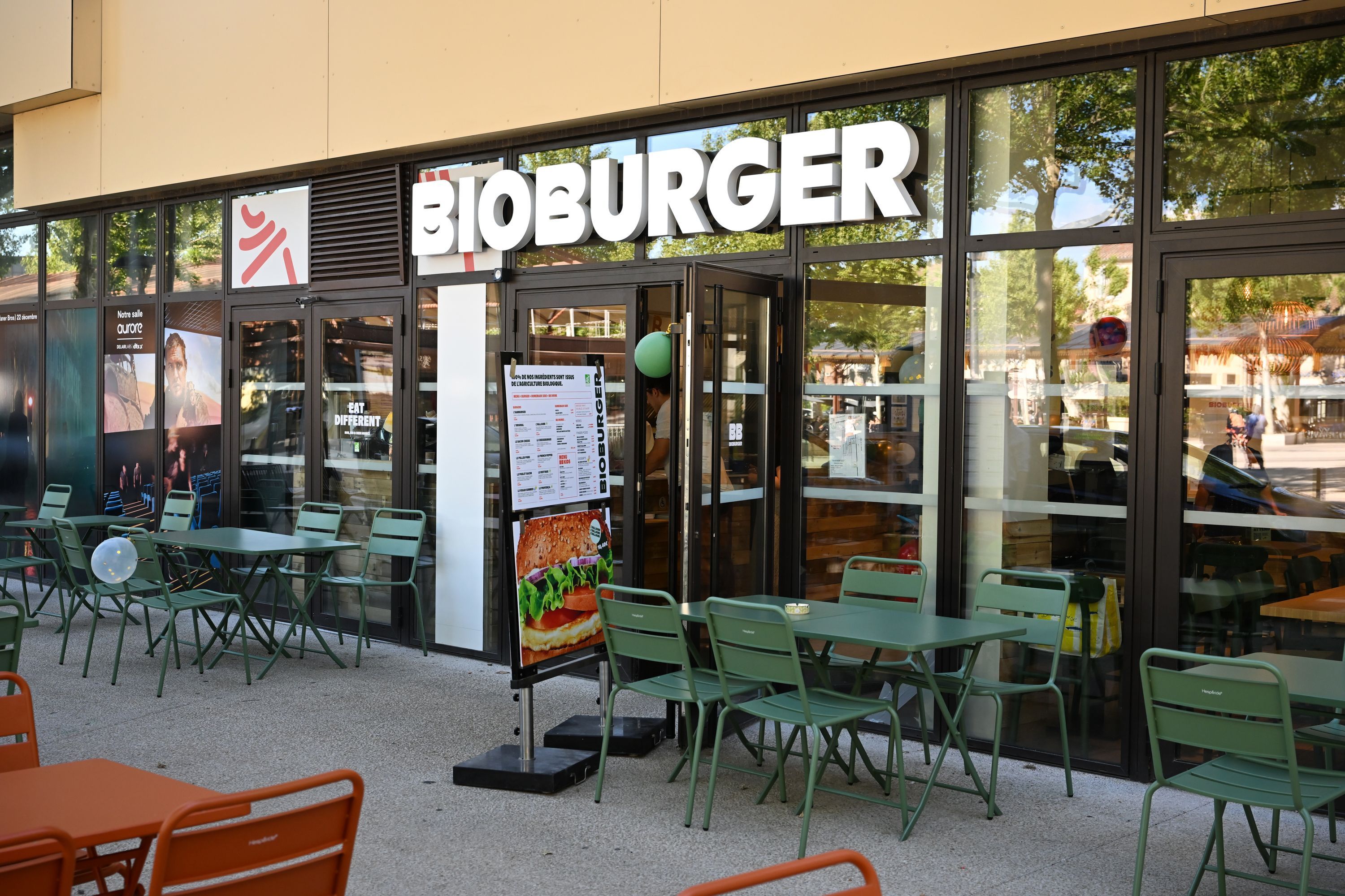 Façade du Bioburger avec des tables vertes, offrant des options bio, véganes et végétariennes.