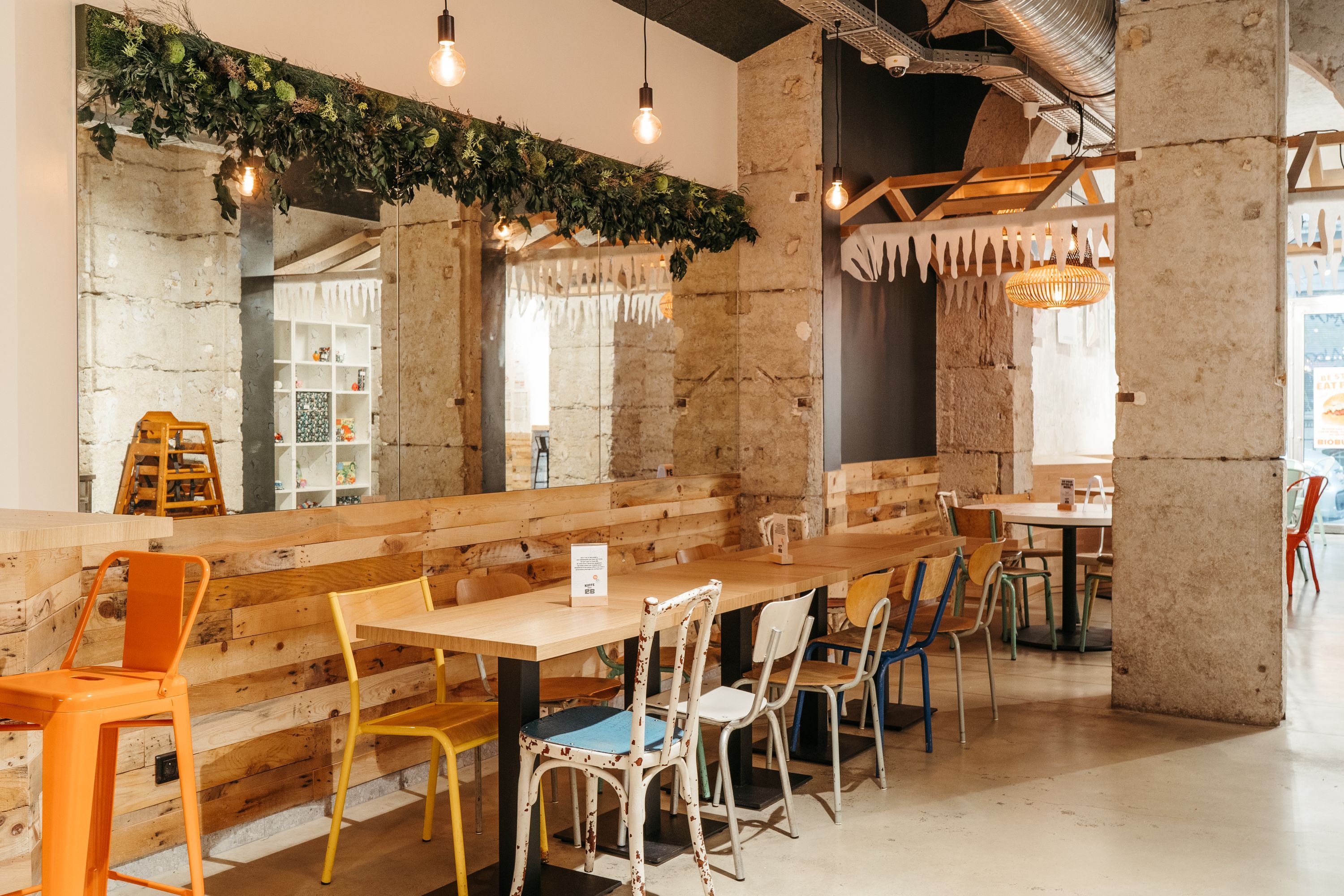 Espace intérieur du restaurant avec des chaises colorées et des tables en bois, ambiance décontractée.