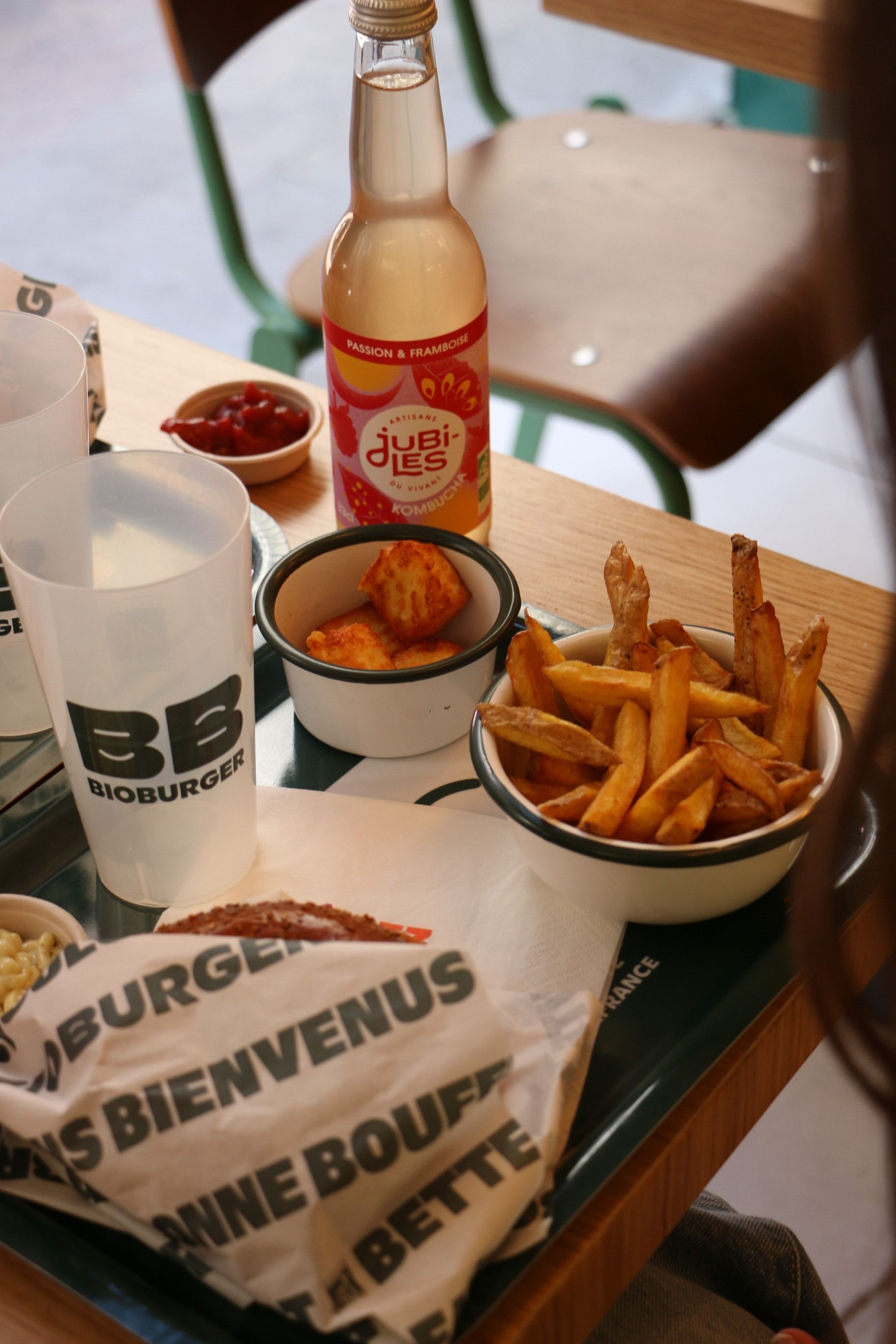 Repas bio avec burger, frites, boisson kombucha et sauces sur une table en bois chez Bioburger Toulouse Carmes.