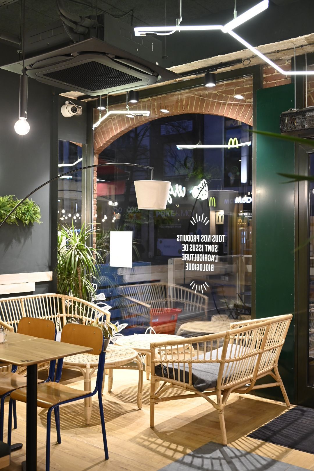 Espace intérieur du restaurant avec des sièges en bois, des plantes et une grande fenêtre.