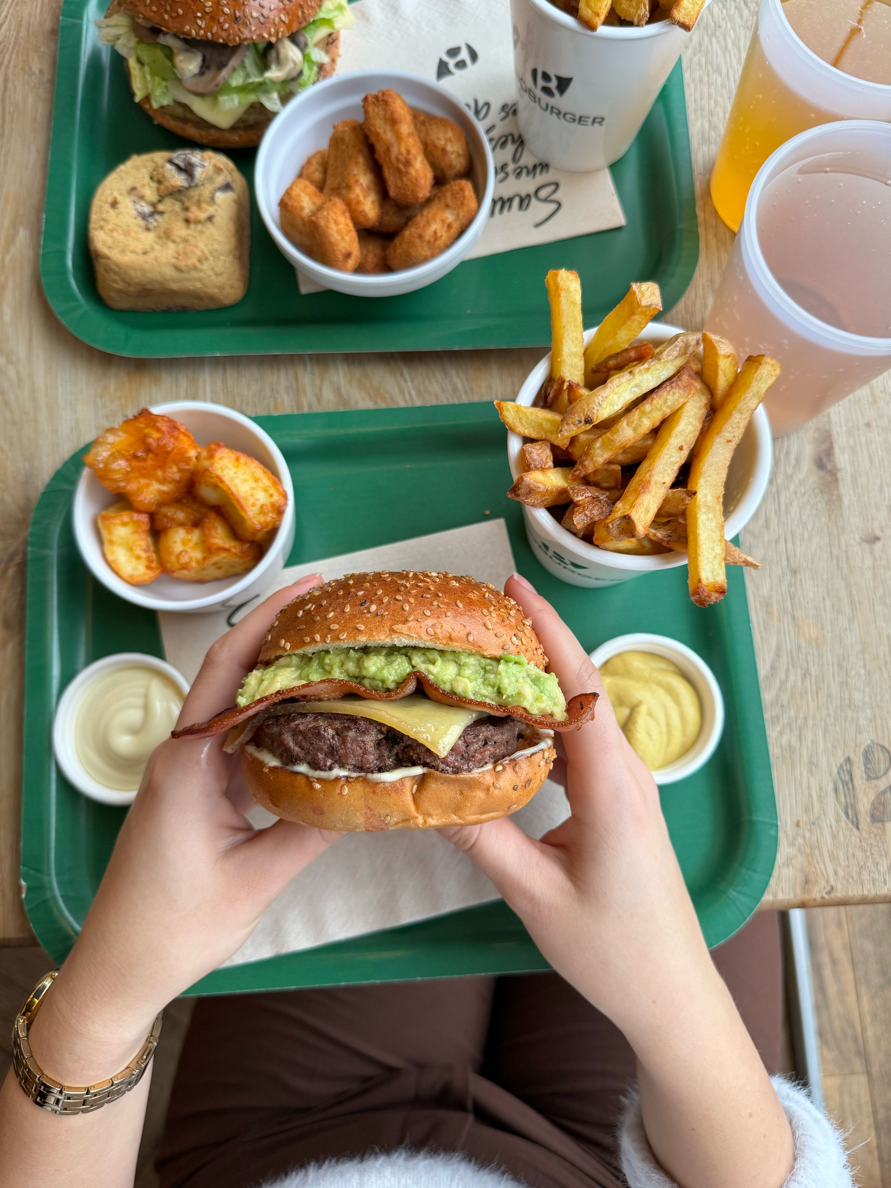 Plateau avec un burger, frites, tenders et desserts, offrant des options bio et végétariennes.