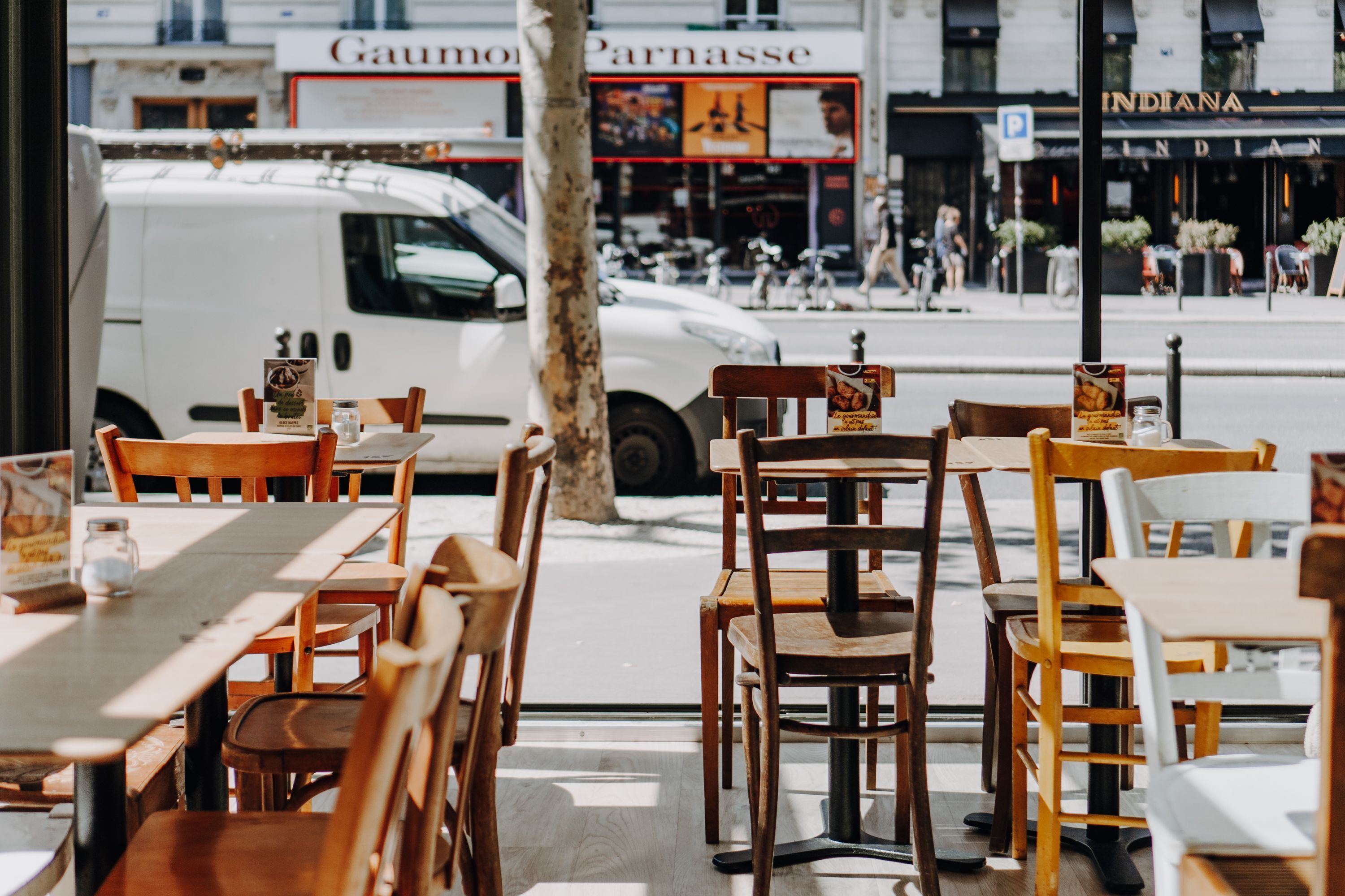 Salle à manger lumineuse avec des tables et chaises colorées, accessible depuis une rue animée.