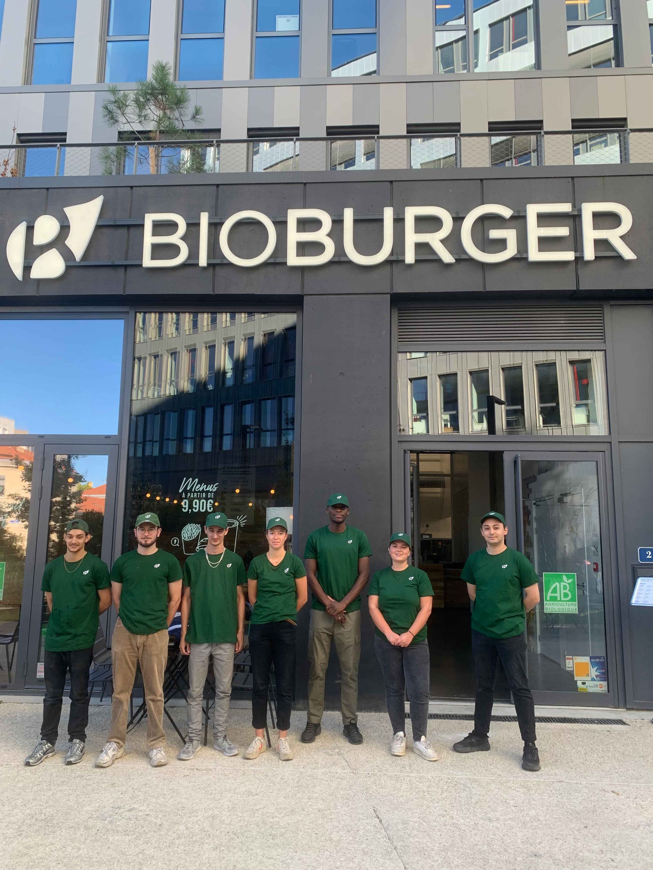 Un groupe d'employés devant le restaurant Bioburger Bordeaux Belcier, portant des vêtements de travail verts.