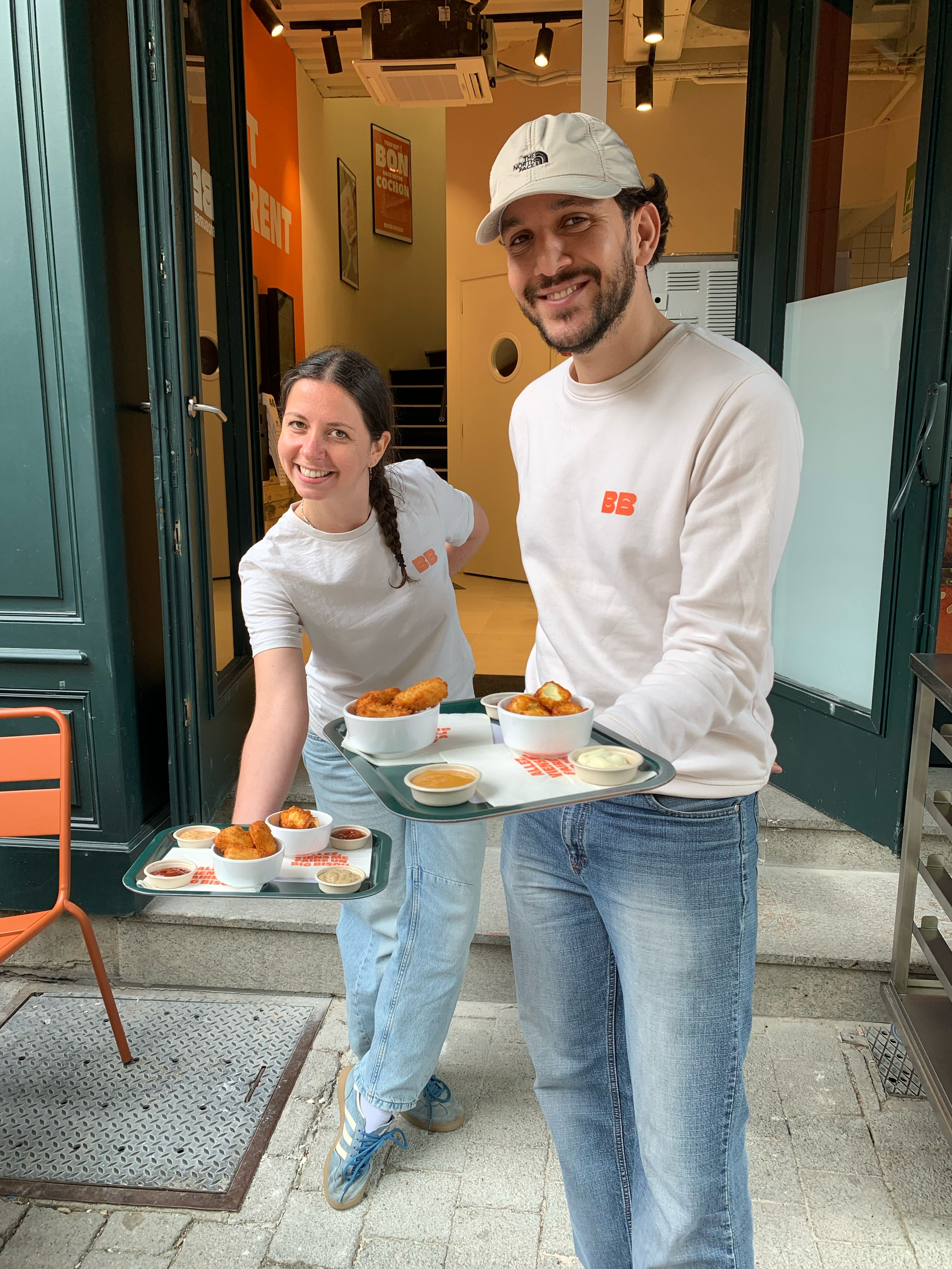 Serveurs présentant des plats de burgers bio, végétariens et vegan avec sauces dans un restaurant.