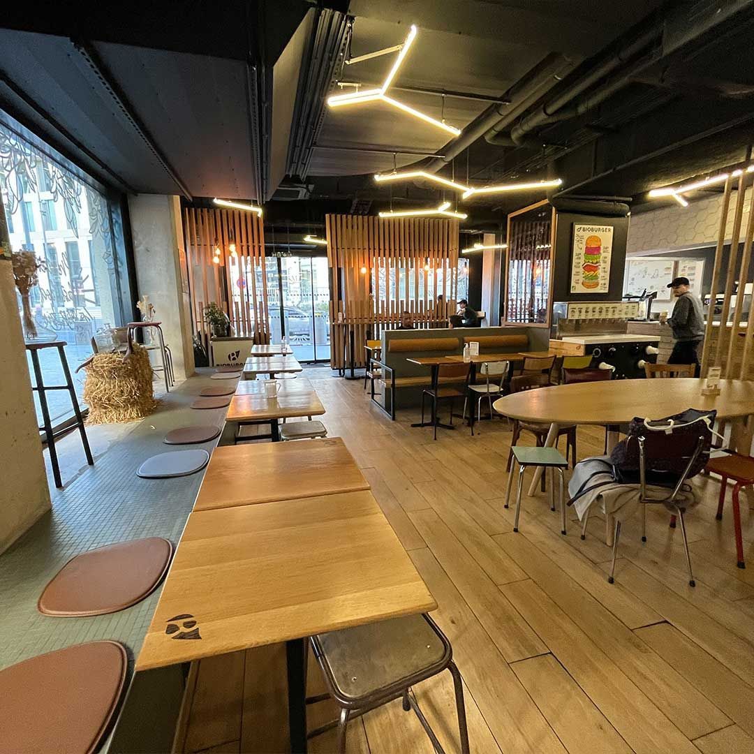 Intérieur du Bioburger Batignolles, avec des tables en bois et un espace lumineux.