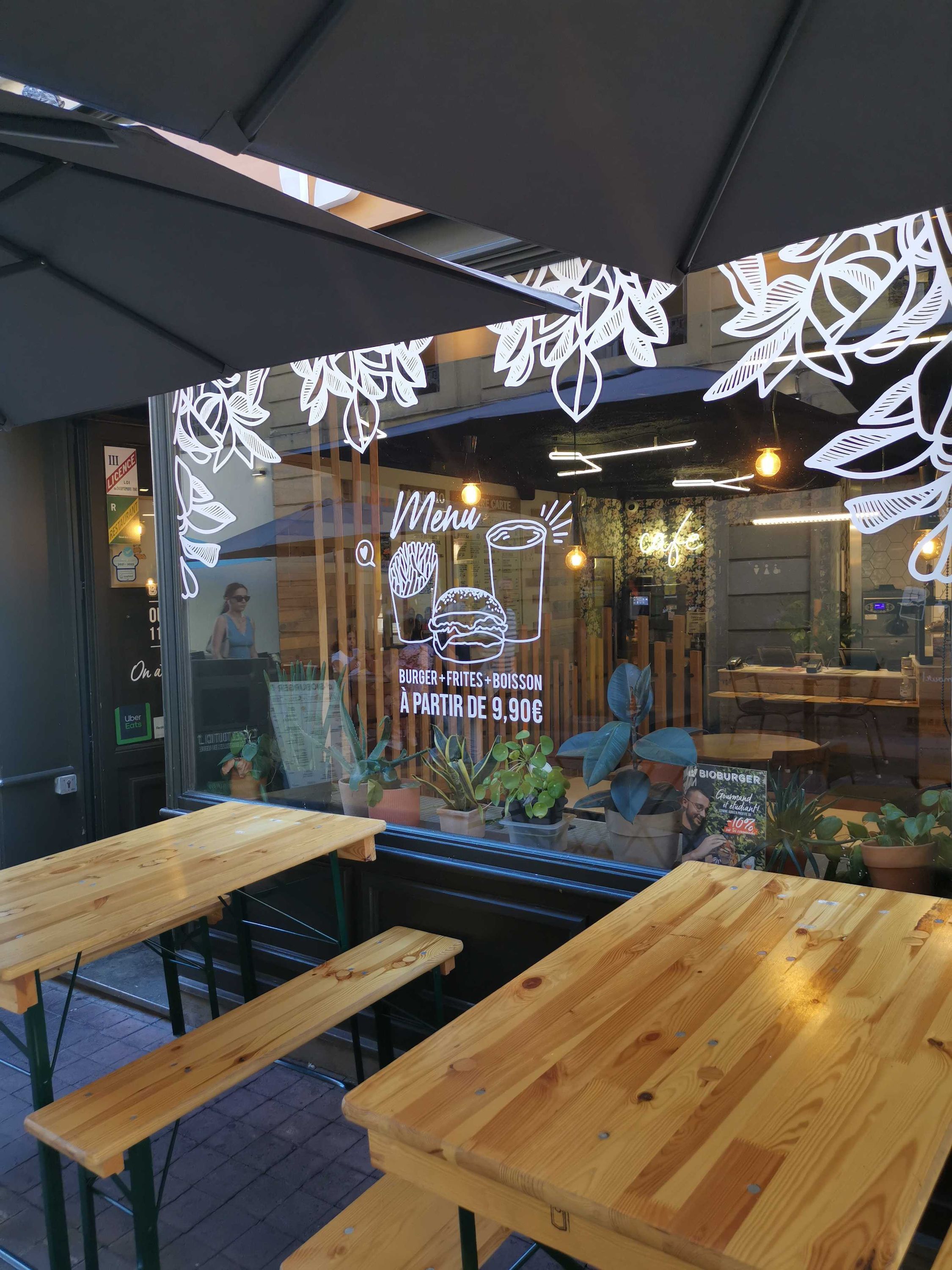 Vitrine du restaurant avec un menu affiché et des tables en bois, offrant des options bio, vegan et végétariennes.