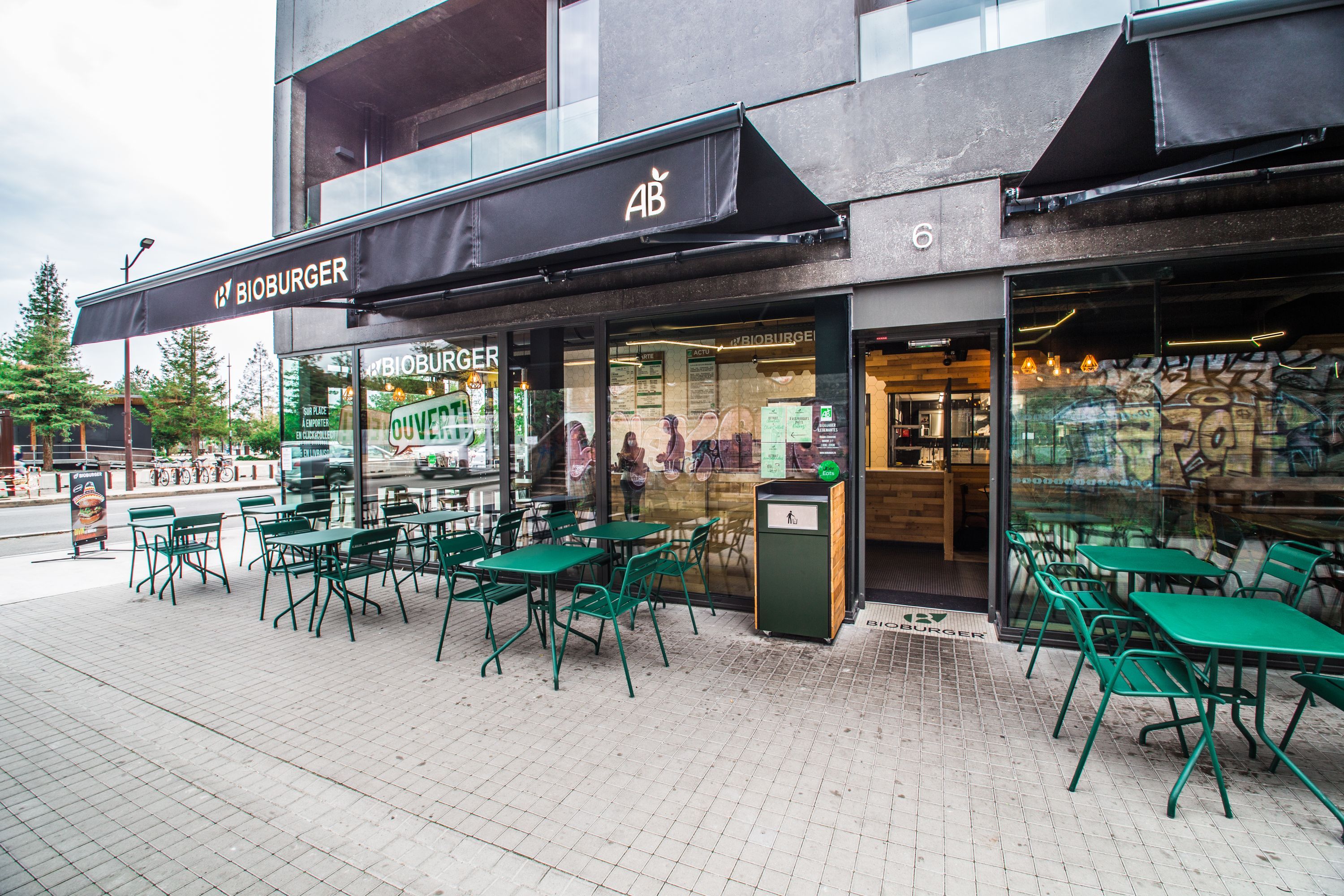 Terrasse extérieure de Bioburger à l'île de Nantes, avec des tables vertes et un espace accueillant.