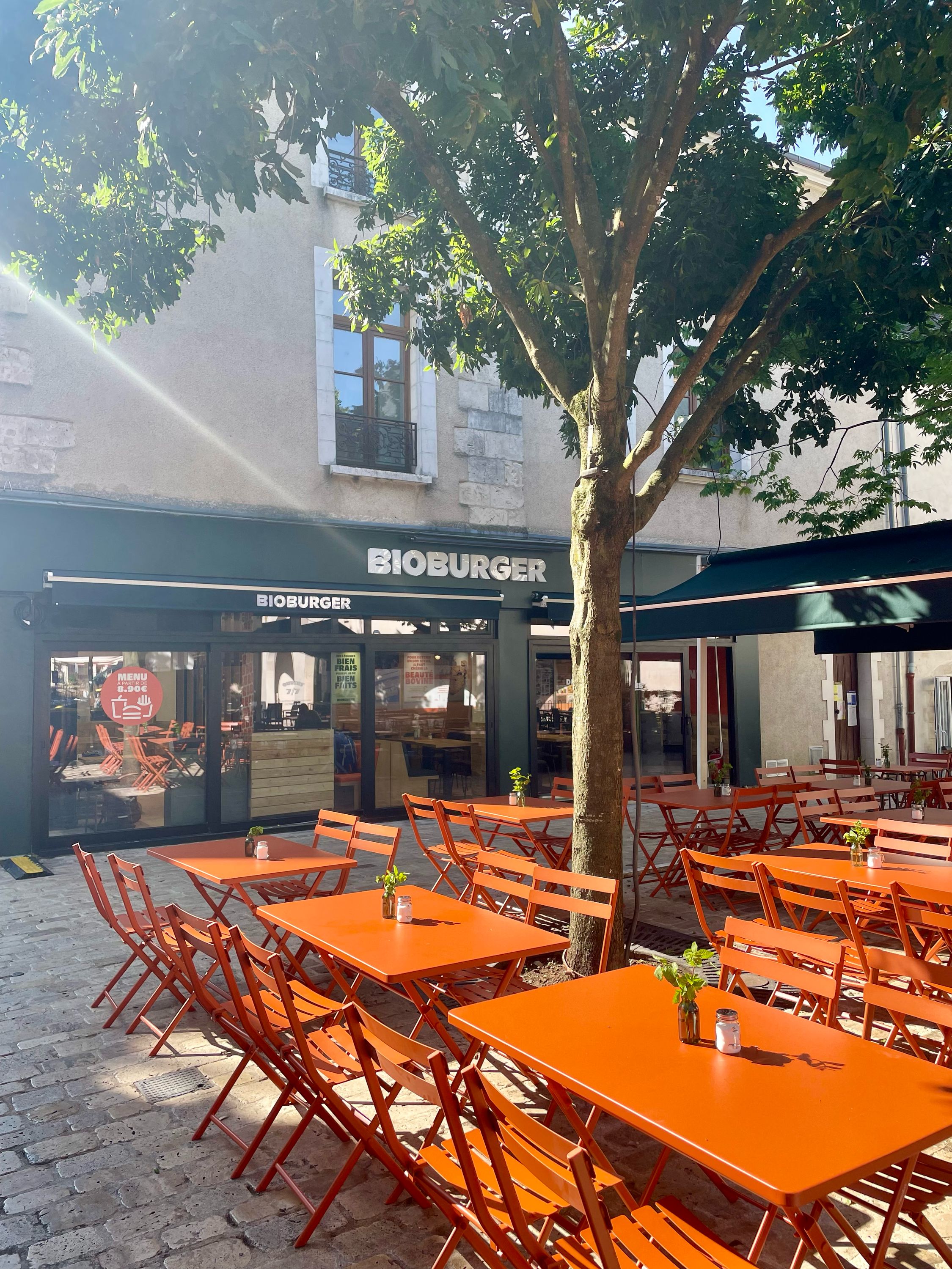 Terrasse du restaurant Bioburger à Orléans, avec des tables orange et un décor végétal, offrant des options bio et véganes.