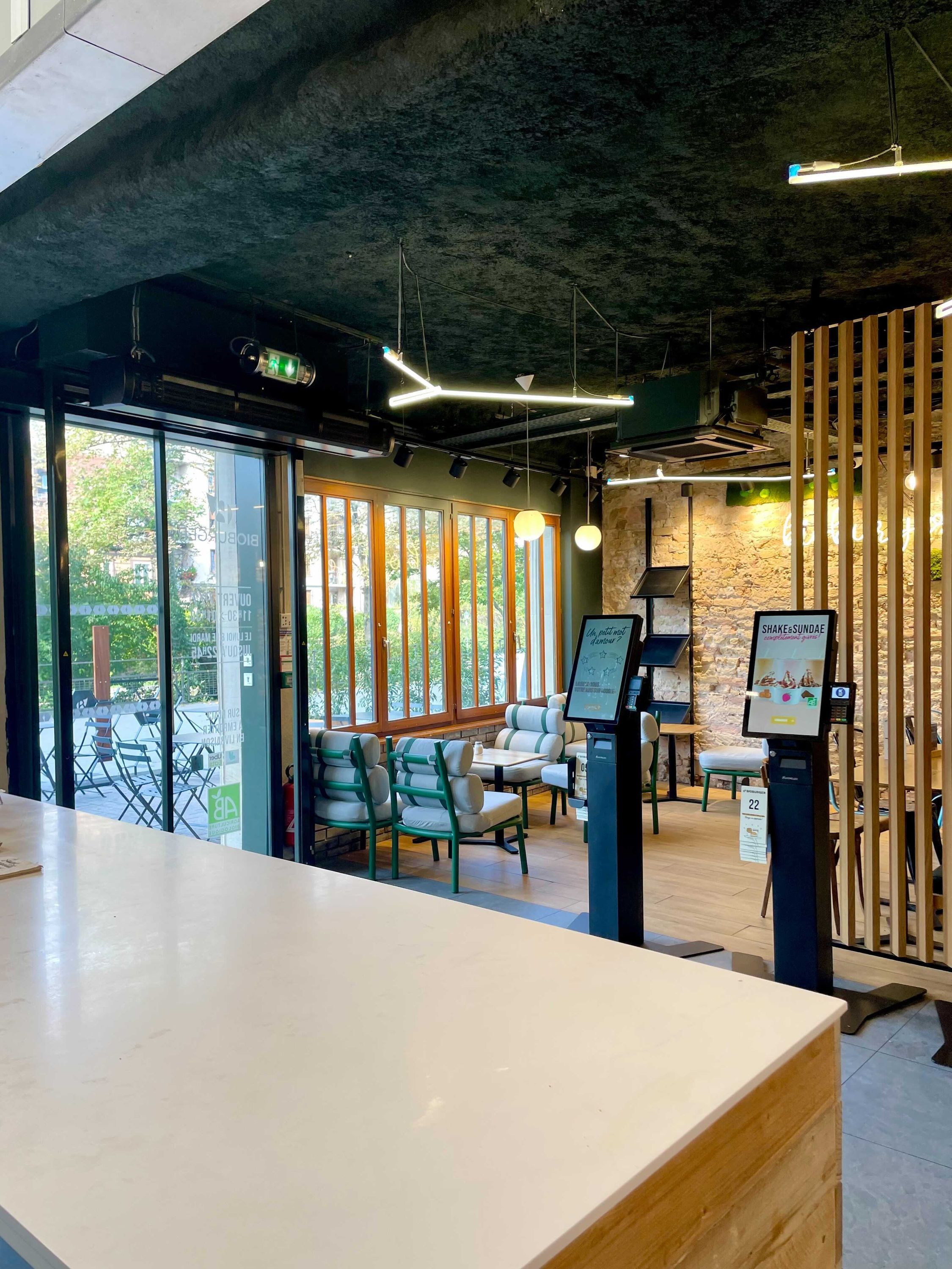 Espace intérieur lumineux avec mobilier moderne et coin végétal, idéal pour déguster un burger bio.