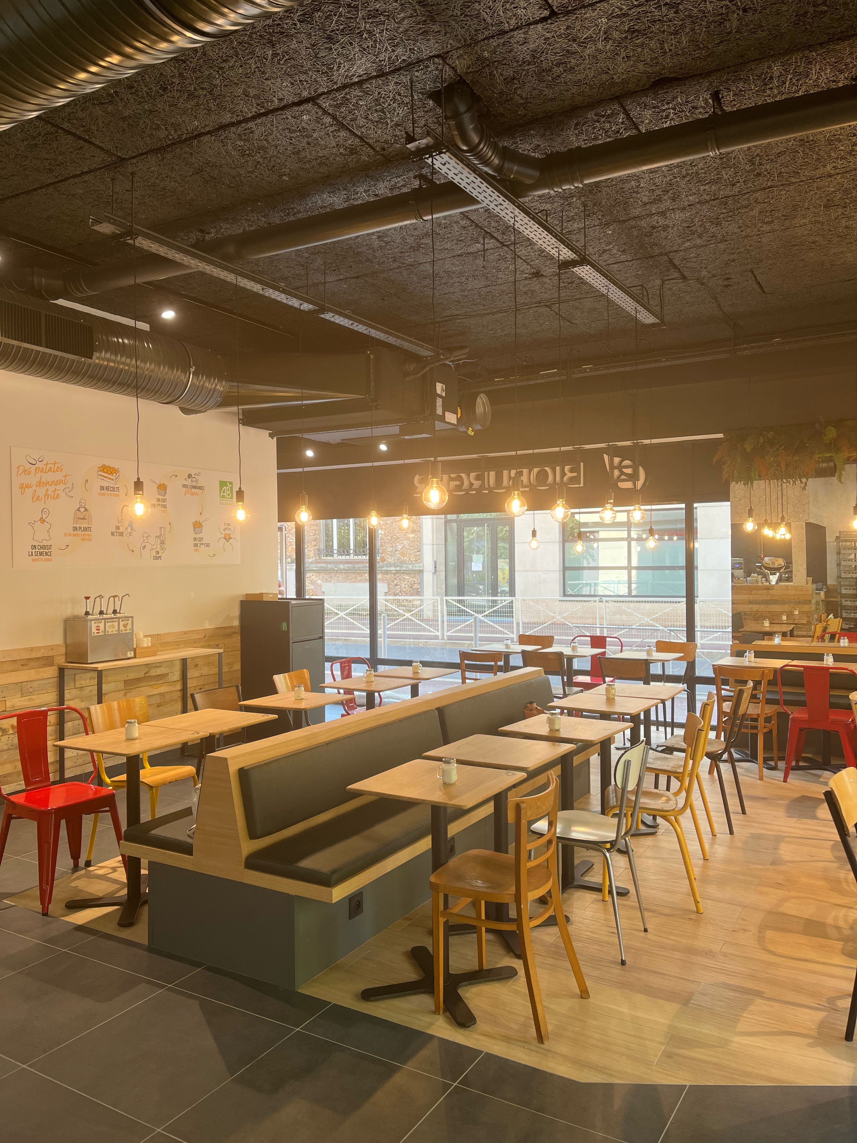 Intérieur du restaurant avec des tables et chaises modernes, ambiante décontractée, éclairage chaleureux.