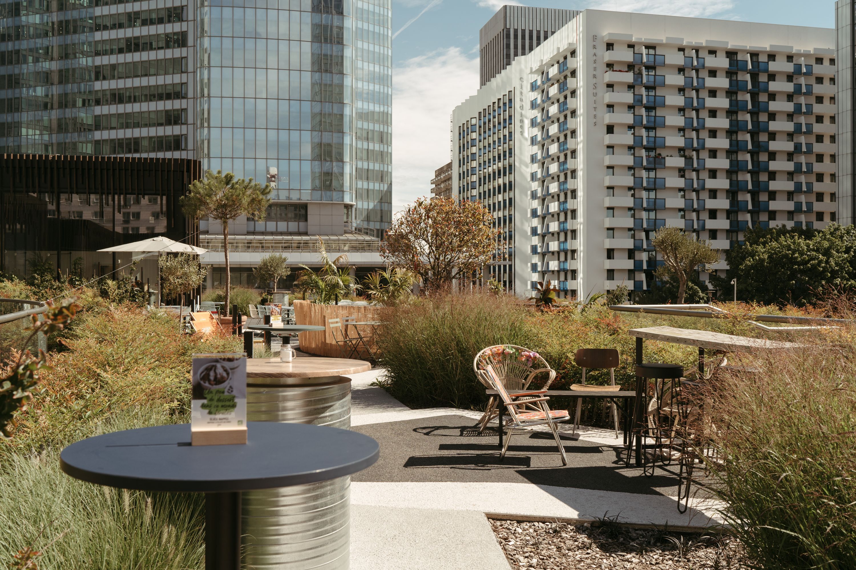 Terrasse extérieure avec des tables et chaises, entourée de verdure moderne.