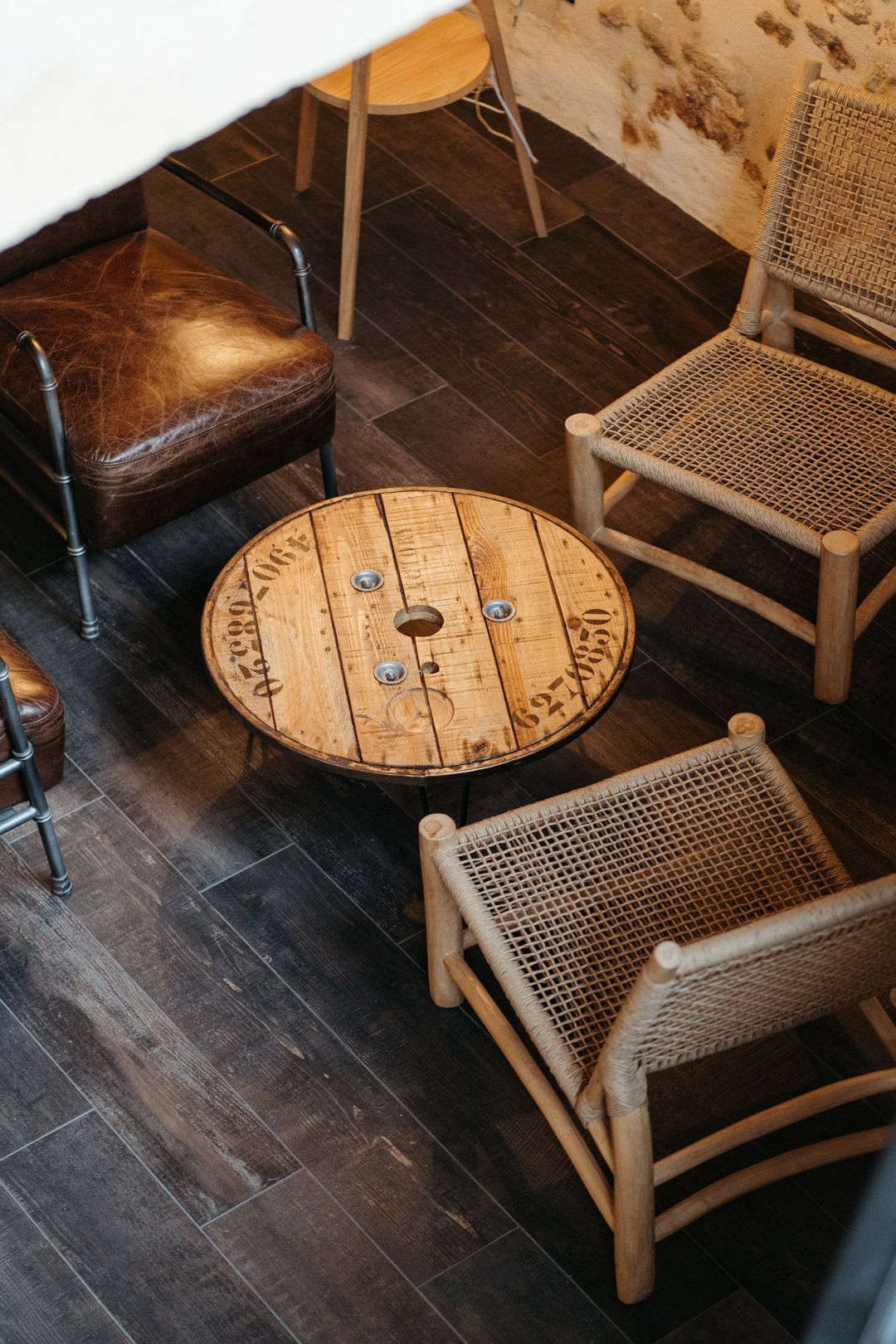 Un coin de salon avec une table en bois circulaire et des chaises en rotin au restaurant Bioburger Bordeaux Gambetta.