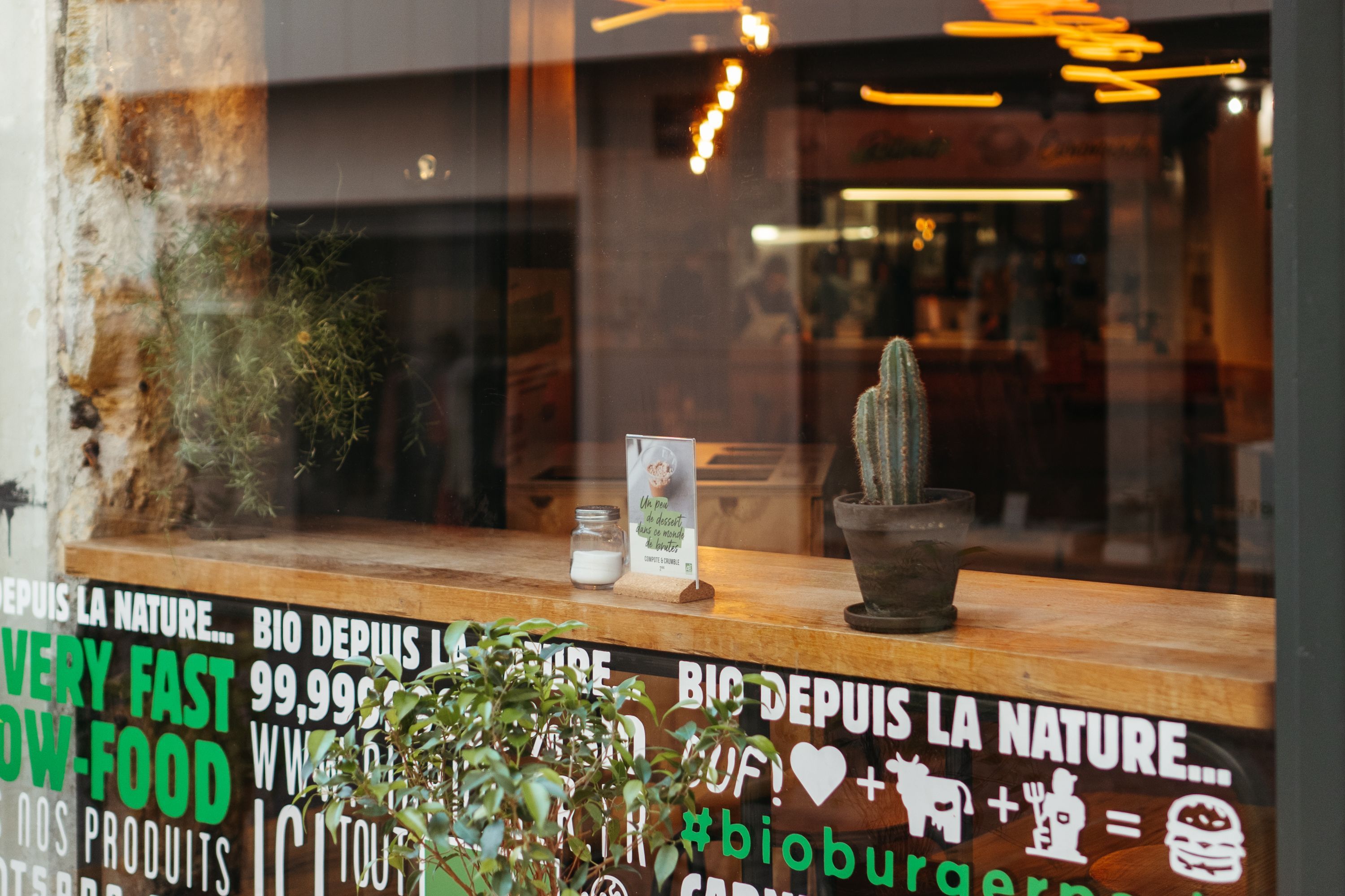 Vitrine du restaurant Bioburger Montorgueil avec des plantes et une décoration axée sur le bio et le végétal.