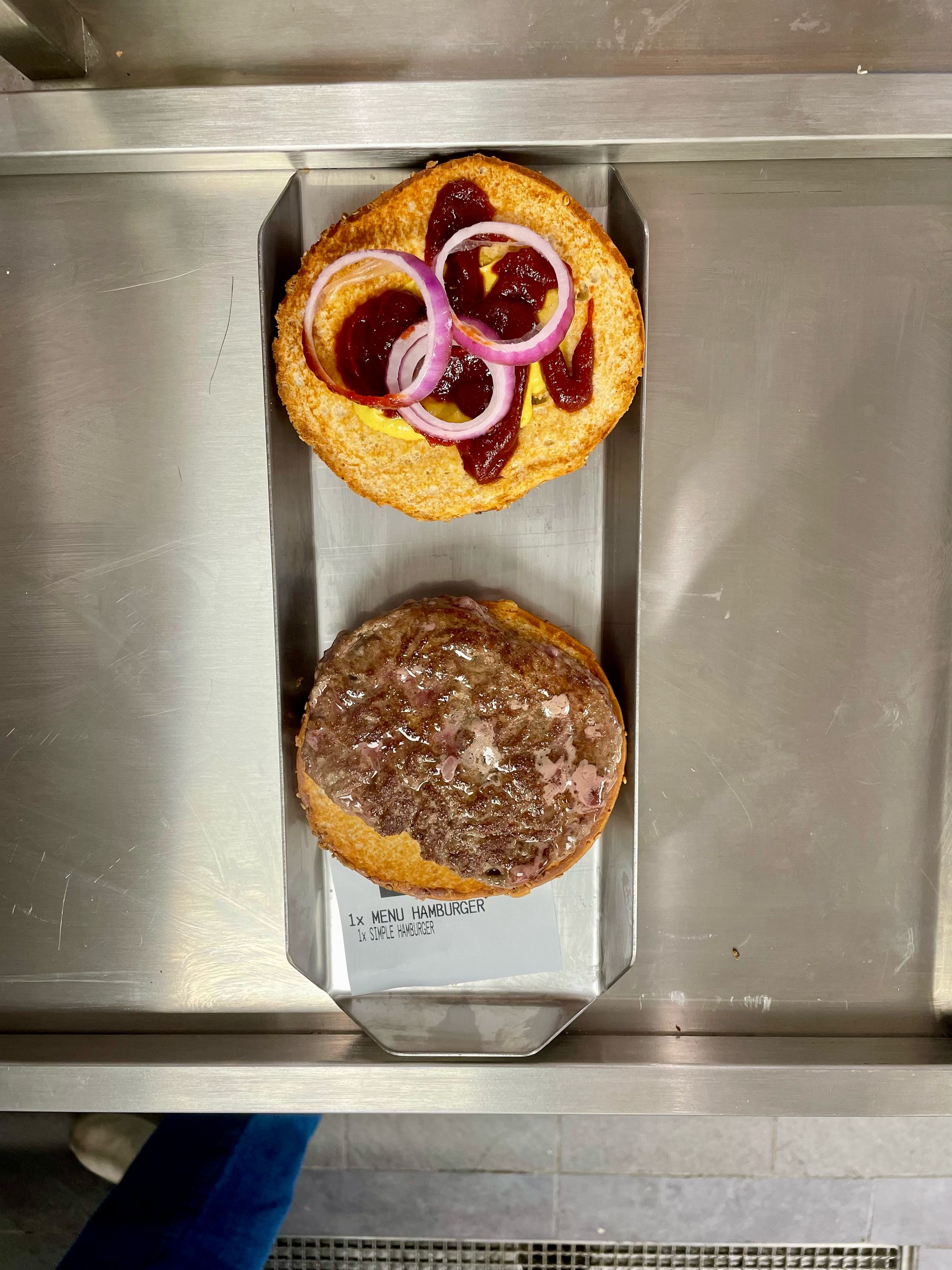 Pain à burger croustillant sur plaque, avec oignons et sauce, prêt pour la garniture.