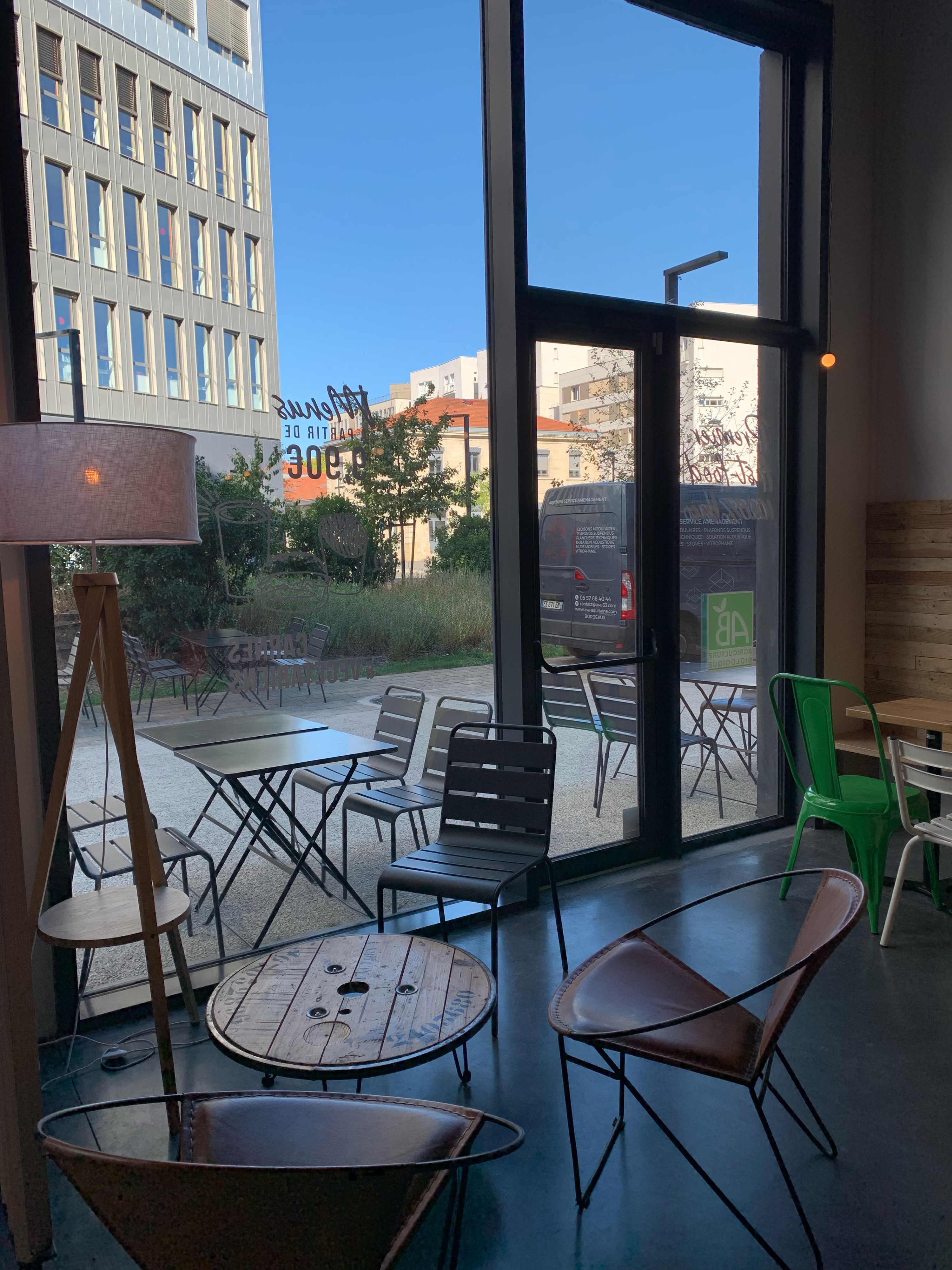 Espace intérieur du restaurant, avec tables, chaises et grandes fenêtres donnant sur l'extérieur.