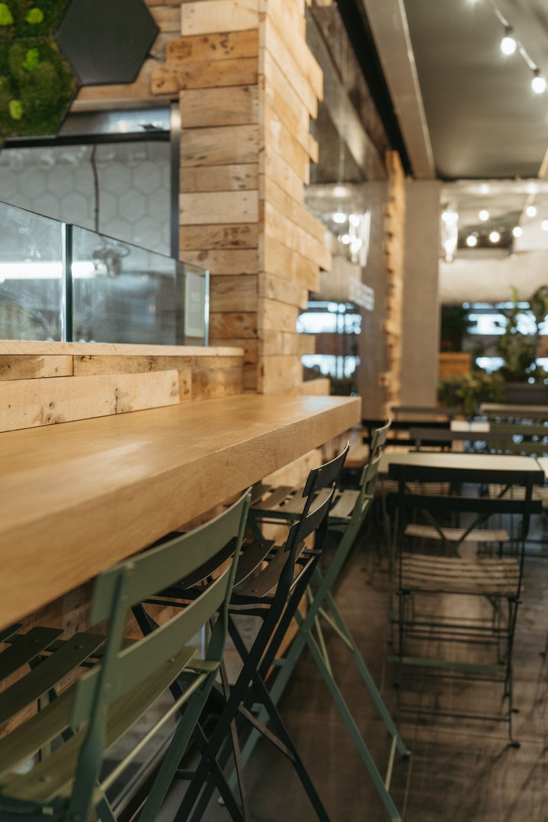 Un intérieur du restaurant avec des chaises en métal et une table en bois, soulignant l'ambiance bio et végétale.
