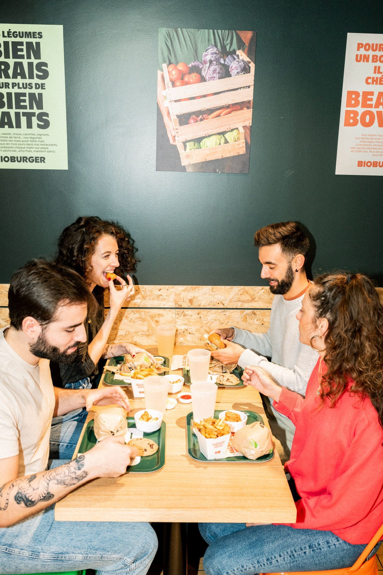 Quatre personnes dégustent des burgers bio et vegan dans un cadre décontracté au restaurant.