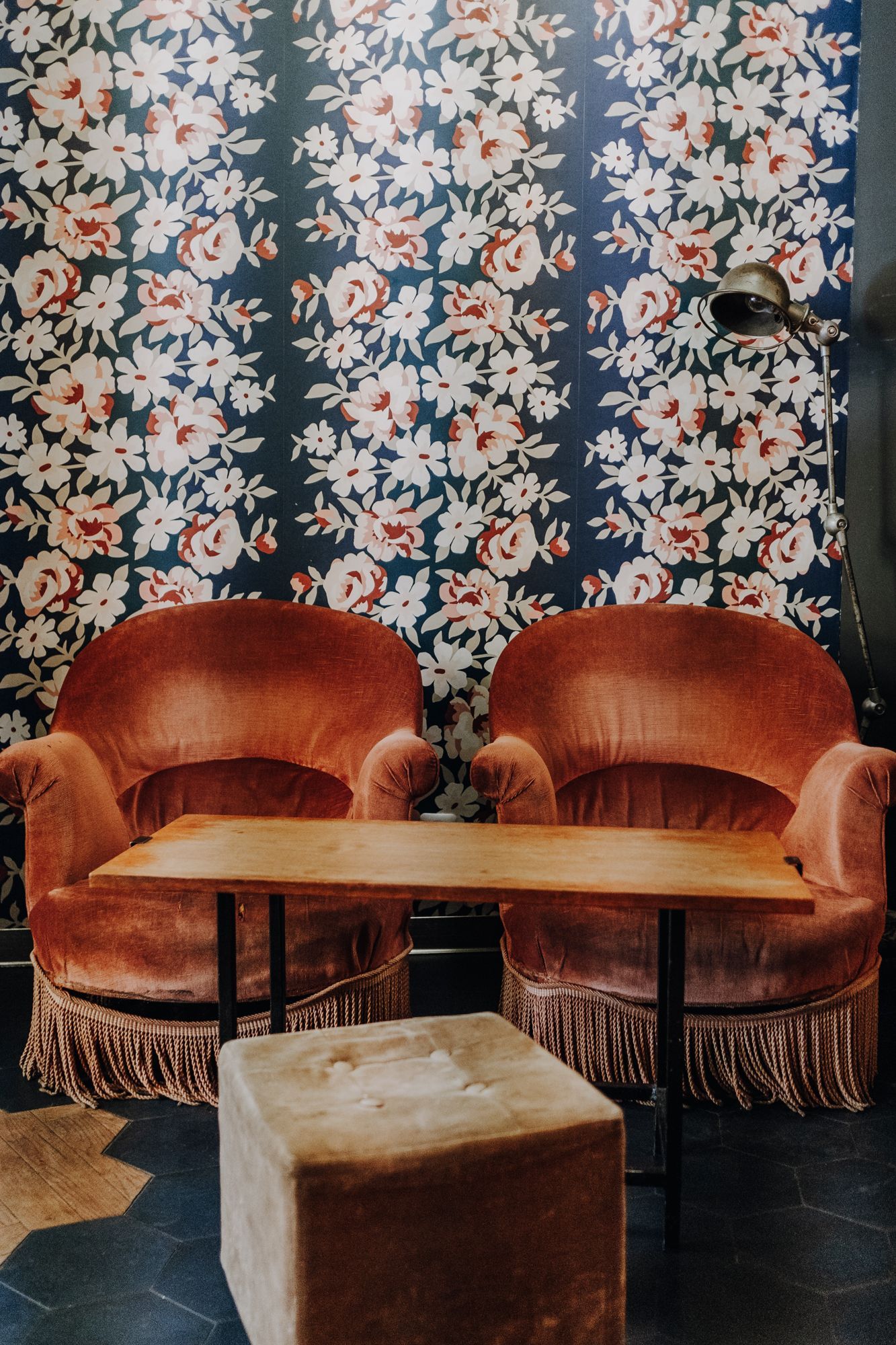 Espace de restauration avec des fauteuils en velours et une table en bois, dans un décor floral.