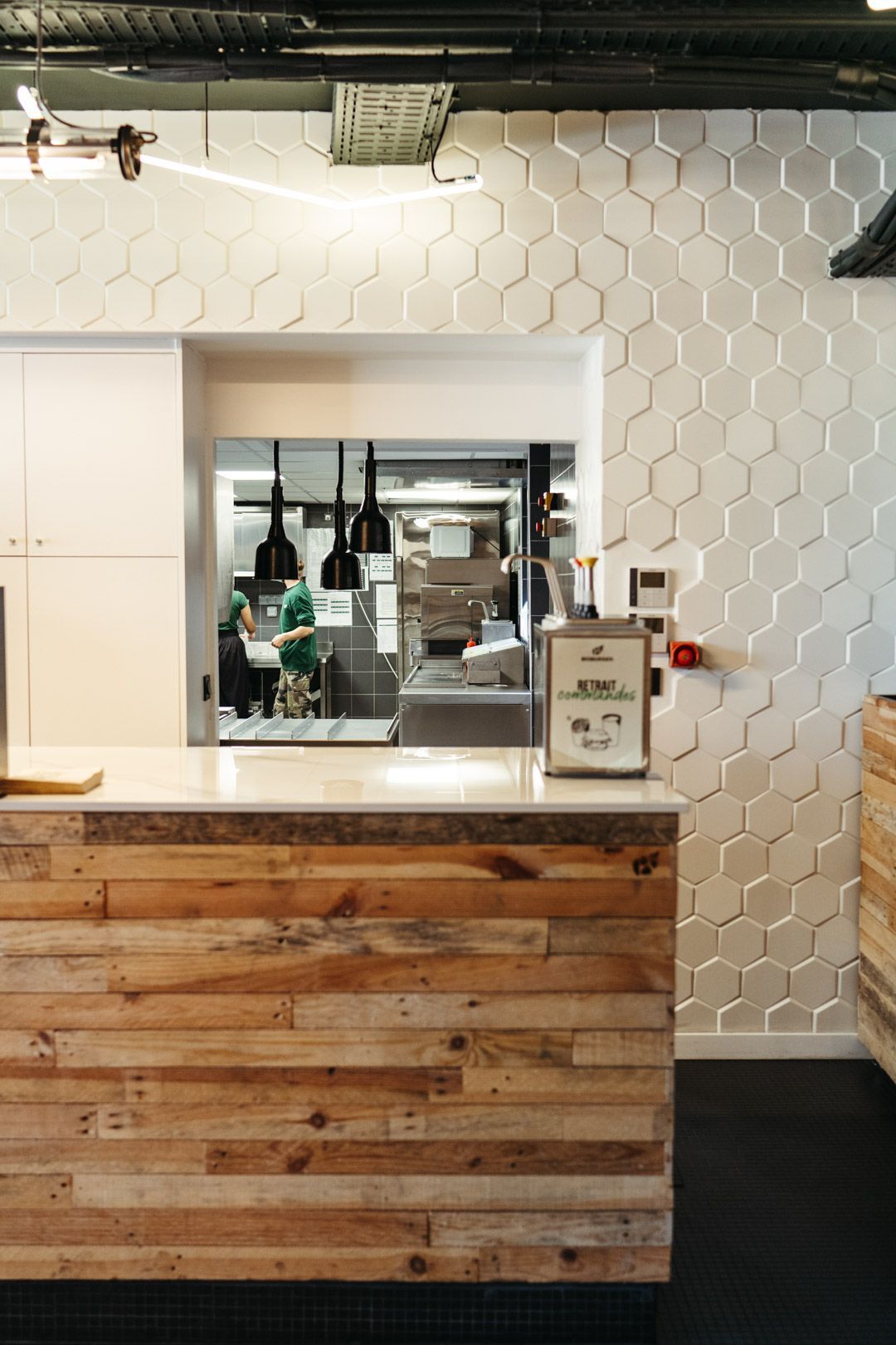 Espace intérieur du restaurant avec un comptoir en bois et des murs en carrelage hexagonal.