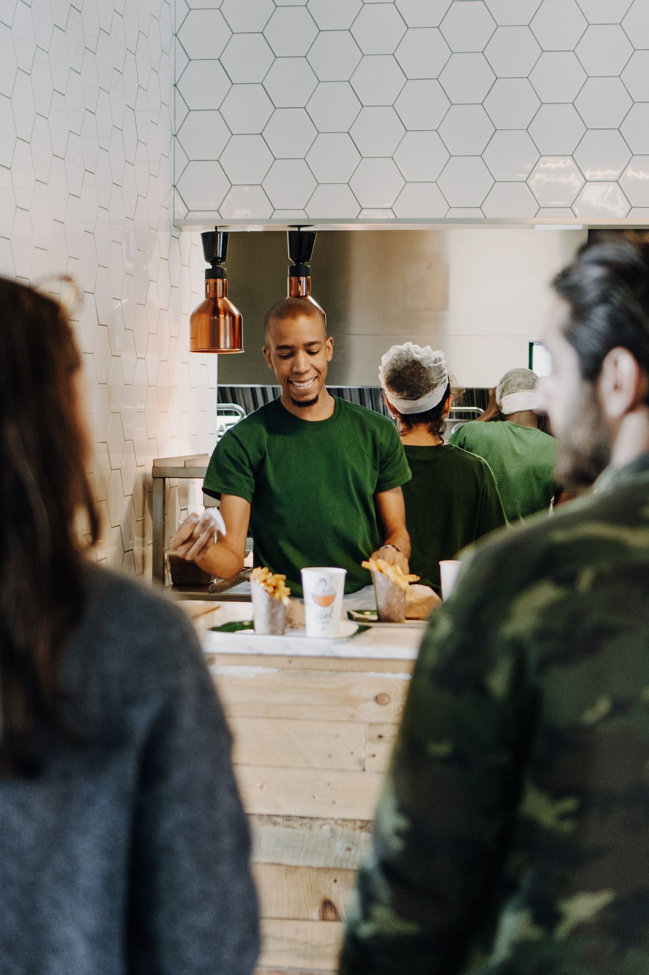 Personnel souriant servant des burgers bio avec des options végétariennes et véganes.