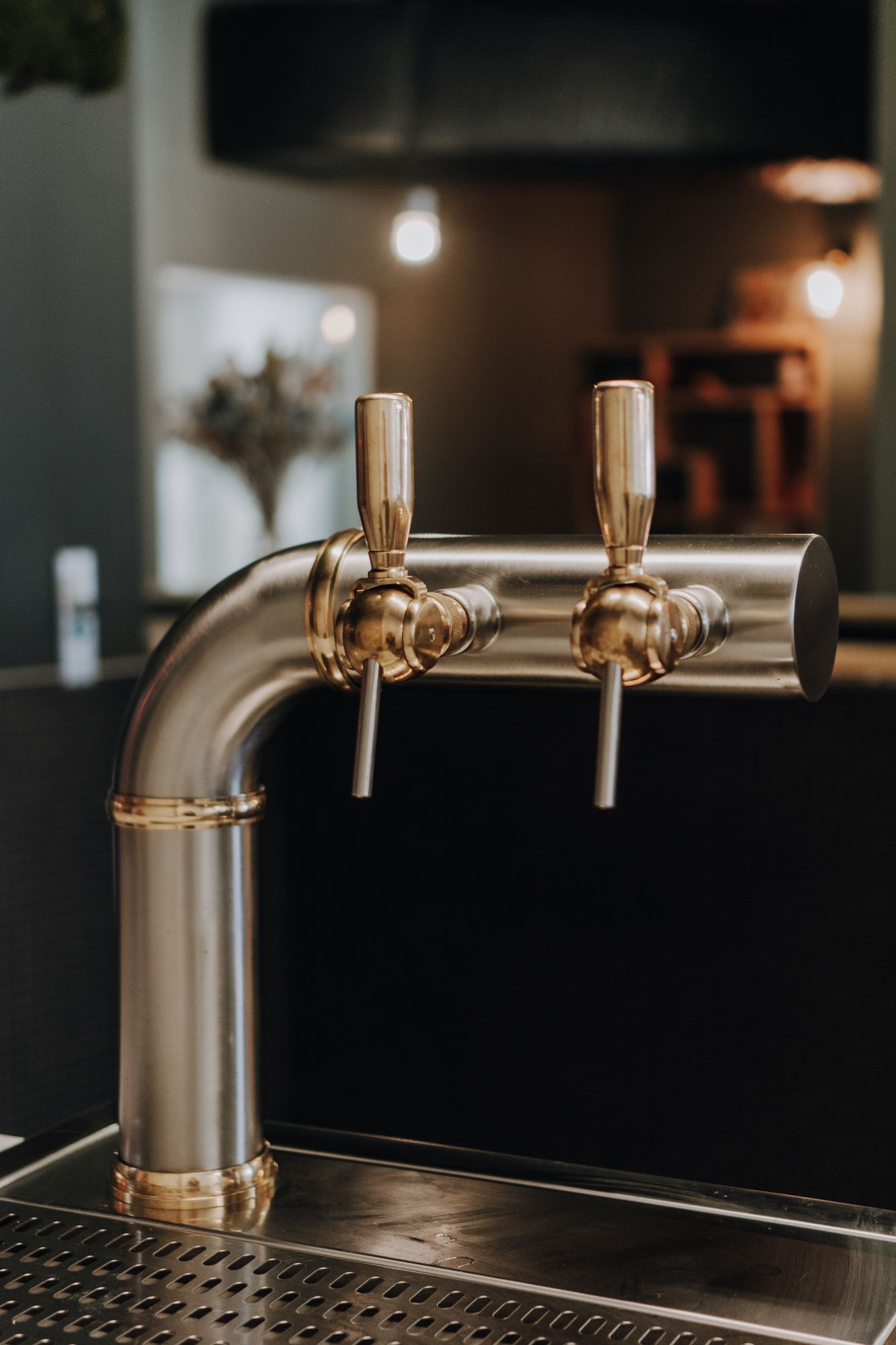 Robinet de bière en acier inoxydable avec deux becs, situé dans un restaurant moderne.